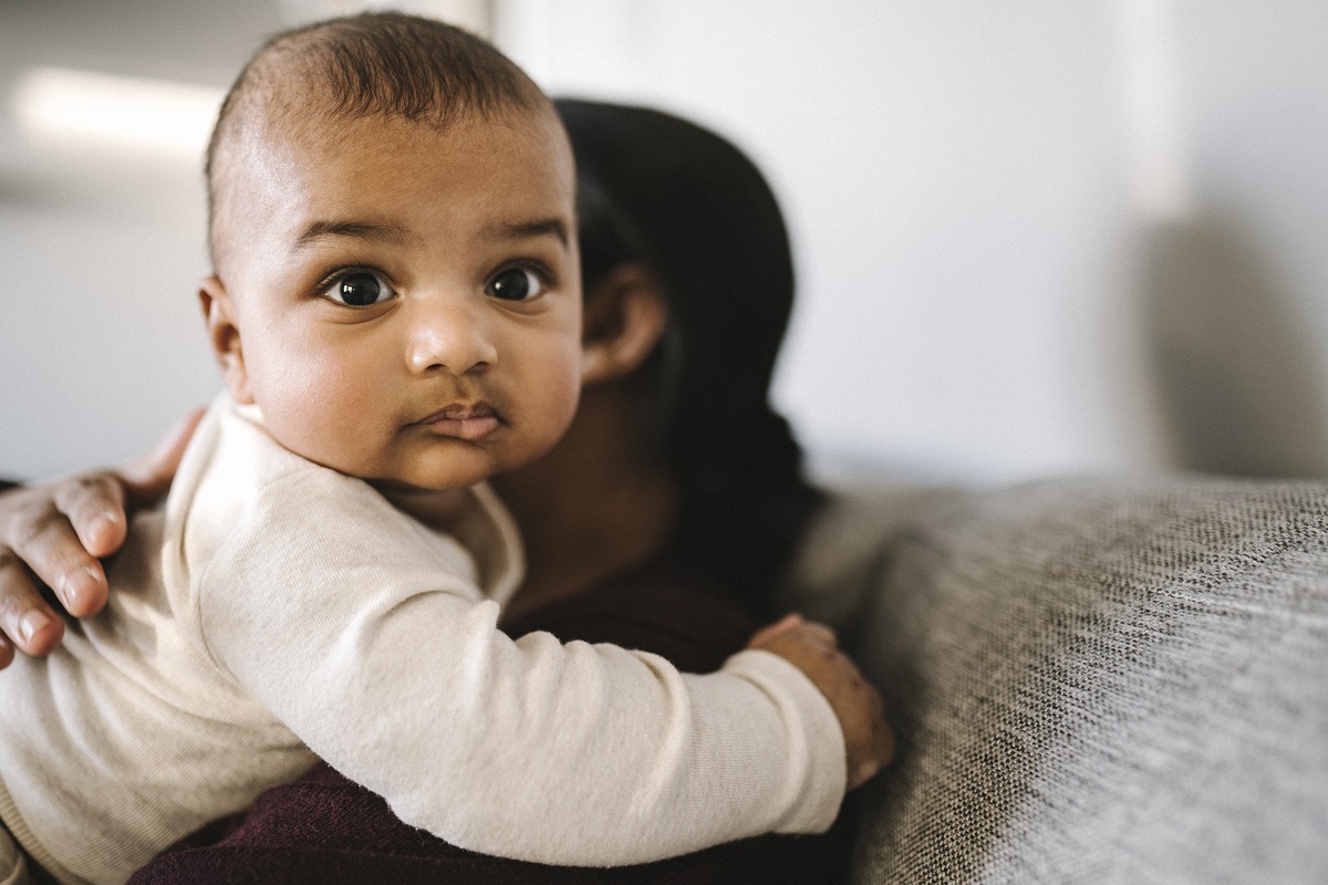 Mother holding a baby sitting at home