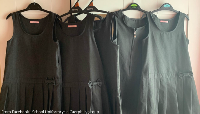 Picture of school pinafores on hangers, hanging from top of a wardrobe