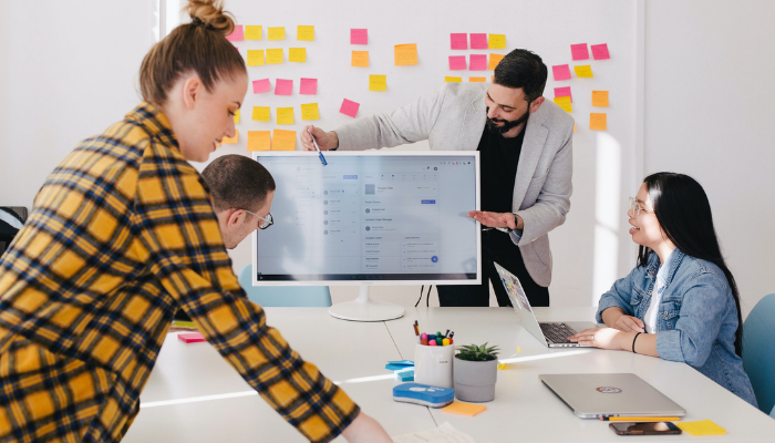 Picture of people having a meeting around a table using screens not paper