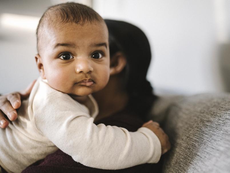 Mother holding baby sitting at home