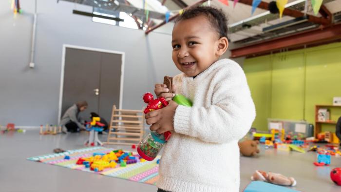Child grasping a few toys and looking at the camera