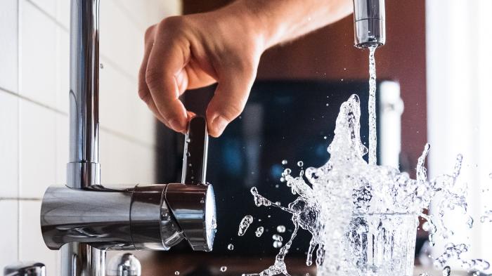 Someone using the kitchen tap to pour a glass of water
